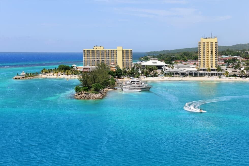 An aerial view of Ocho Rios, Jamaica, with bright blue water, boats, and coastal resorts for Boardwalk Resort Vacations Caribbean destinations.